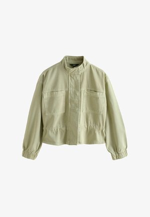 Lys khaki jakke med høj krave, to brystlommer, elastiske ærmeafslutninger og en indsnørret talje, vist fladt på en hvid baggrund.