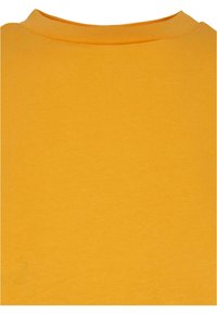Zone de l'encolure ras-du-cou d'un t-shirt en coton uni jaune-orange montrant la texture du tissu et les détails des coutures.