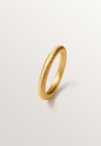 Anillo de oro con un acabado mate suave, con forma redondeada y una textura uniforme, sobre un fondo neutro.