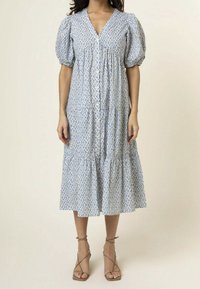 Blue and white patterned midi dress with puff sleeves, V-neck, and button closure. Features tiered ruffle hem and lightweight fabric.