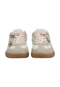 Paire de baskets blanches et beiges avec des lacets roses, des semelles marron et de petits charms en métal attachés aux lacets.
