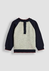 Strickpullover mit hellem grauem Körper, dunkelblauen Raglanärmeln, roten Akzenten am Kragen und Saum, mit einer Knopfnaht hinten.