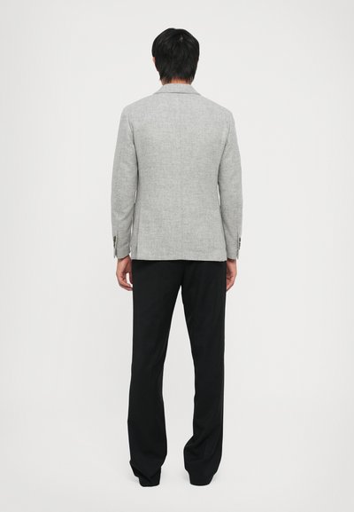 Gray textured blazer with a tailored fit, single vent at the back, and black trousers, shown from the back.