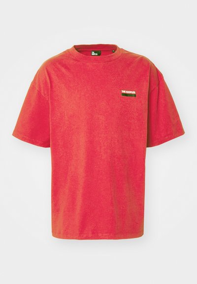 Rød bomulds T-shirt med korte ærmer, rund halsudskæring og et lille rektangulært logo-patch i sort og hvid på venstre bryst.
