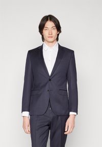 Marineblauwe blazer met een notched lapel en enkele knoopsluiting, gecombineerd met een witte overhemd met kraag. Smooth stof, minimalistisch ontwerp.