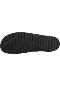 Suola di scarpa nera con una superficie in gomma testurizzata, caratterizzata da profonde scanalature per la trazione e con il logo del marchio impresso al centro.