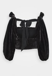 Černý sametový top s balónovými rukávy, který má nařasený korzet, otevřený zadní díl a nastavitelné šňůrky na rameni pro bezpečné uchycení.