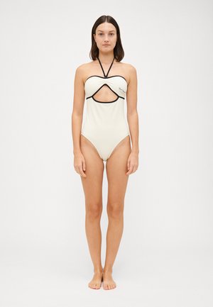 Cream-colored one-piece swimsuit with a cutout design, black accents around the neckline and cutout, and halter straps.