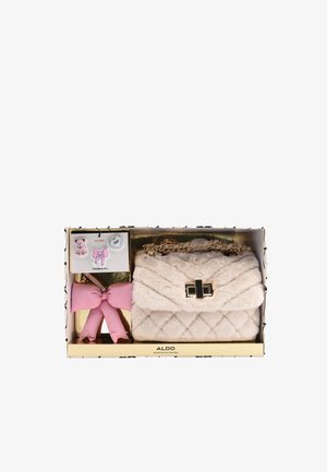 Zachte beige gewatteerde crossbodytas met gouden ketting, roze strik sleutelhanger en drie decoratieve speldjes waaronder een teddybeer, strik en hart.