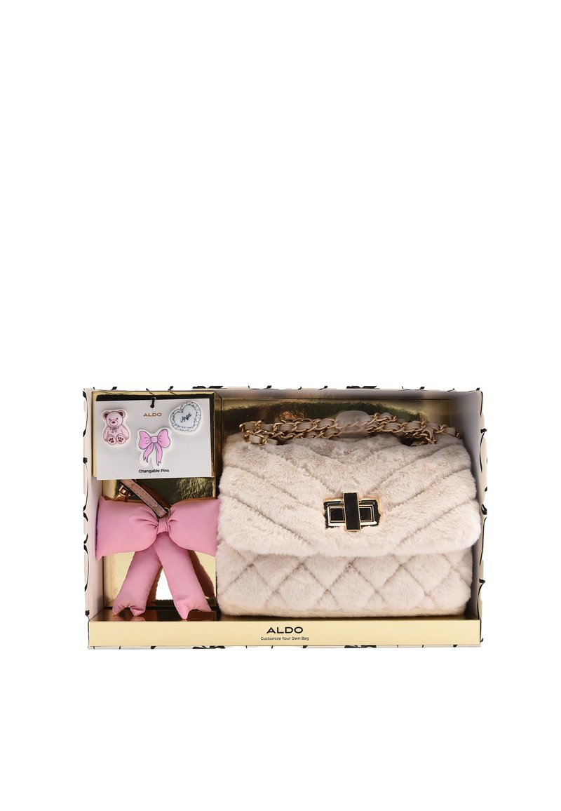 Miękka beżowa pikowana torebka na ramię z złotym łańcuszkiem, różowym brelokiem w kształcie kokardki oraz trzema ozdobnymi przypinkami: misiem, kokardą i sercem.