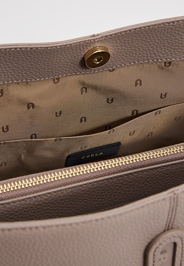 Beżowa skórzana torebka z złotym zamkiem błyskawicznym, zapięciem na zatrzask oraz wzorzystym wnętrzem z tkaniny, z metką marki Furla.