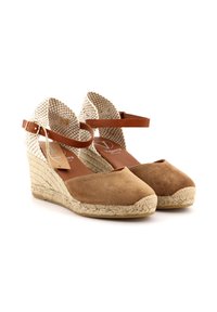 Sandali wedge in suede marrone con cinturini alla caviglia intrecciati beige e fibbie regolabili. Suola in gomma con dettagli in juta. Design a punta chiusa.