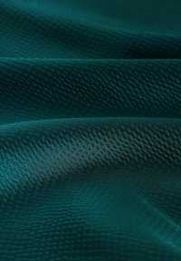 Teal tekstureret stof med en glat finish og et subtilt geometrisk mønster, der hænger elegant i bløde folder.