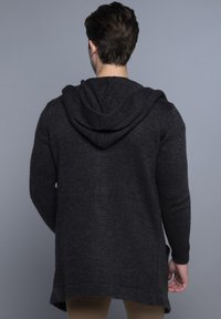 Donkergrijze gebreide hoodie met een gestructureerde afwerking, voorzien van een capuchon en een langere achterkant. De mouwboorden en de onderrand zijn geribbeld.