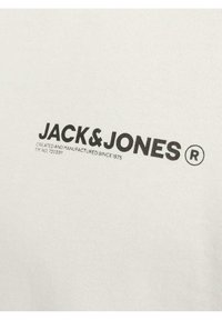 Camiseta de algodón blanca con un logo impreso en negro "JACK & JONES" y un eslogan debajo. Textura simple y suave, diseño de cuello redondo.