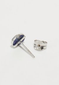 Orecchini in argento con una pietra rotonda in lapislazzuli dalla finitura lucida e un design elegante a singolo chiodo, accompagnati da un cerchio coordinato.