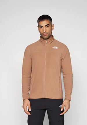 Light brown zip-up fleece jacket with a high collar, two side pockets, and a subtle logo on the upper left chest. Soft texture.