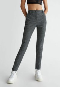 Sorte og hvide ternede bukser med slim fit, der har en flad front, bæltestropper og sidelommer, parret med hvide sneakers.