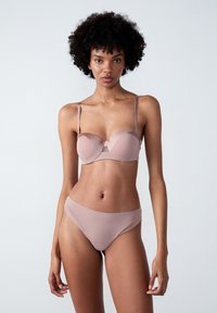 Set di reggiseno e slip in rosa chiaro. Il reggiseno presenta ferretti, coppe sagomate e spalline regolabili. Tessuto liscio, cuciture minime e una leggera lucentezza.