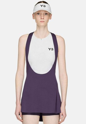 Junge Frau trägt ein ärmelloses lila-weißes Sportkleid mit Y-3-Logo und einem weißen Y-3-Visier, steht vor einem schlichten Hintergrund.