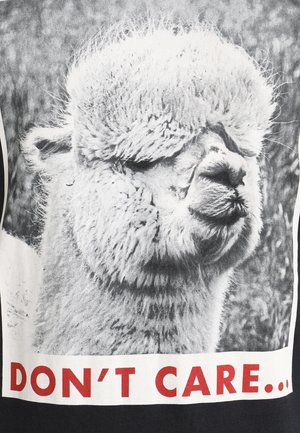 Puszysta głowa alpaki z obojętnym wyrazem w odcieniach szarości, opisana pogrubionym czerwonym napisem "NIE OBCHODZI MNIE TO.."