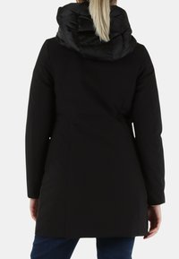 Giacca esterna nera con cappuccio trapuntato e imbottito. Presenta una vestibilità aderente, maniche lunghe e una texture liscia. Nessun hardware o dettagli visibili.