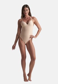 Costume intero nudo con spalline sottili, scollatura a V profonda e una texture liscia e elastica. Progettato per una silhouette aderente.