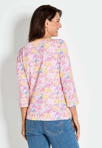 Bunt bedruckte Bluse mit Dreiviertelärmeln, aus leichtem Material. Sie hat einen runden Ausschnitt und einen lockeren Schnitt.