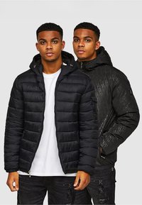 Czarna kurtka puchowa z kapturem, z przeszywanymi panelami i zamkiem z przodu, wyświetlana obok teksturowanej czarnej kurtki z geometrycznymi wzorami.