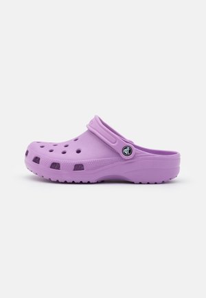 Sabot violet clair à enfiler avec des trous de ventilation et une bride réglable, présenté de côté sur fond blanc.