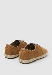 Zapatos casuales de ante marrón con suela de yute trenzada y acentos de piel. Presentan ojetes de metal y un diseño de punta redonda.