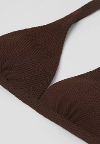 Hnědý bikiny top s texturovanou tkaninou, trojúhelníkovými košíčky a designem pletených popruhů. Obsahuje jemné nařasení uprostřed.