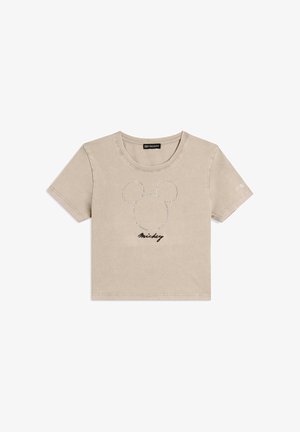 Camiseta corta de manga corta beige con contorno punteado de la cabeza de Mickey Mouse y el texto "Mickey" debajo, en el centro frontal.