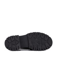 Suola di scarpa in gomma nera con un motivo di battistrada testurizzato, caratterizzato da scanalature profonde e lobi multidirezionali per trazione e aderenza.