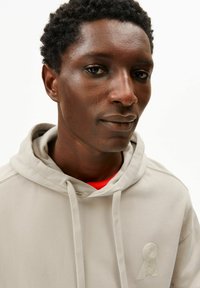 Beige hoodie met een gestructureerd logodetail. Voorzien van verstelbare trekkoorden en een zachte katoenmengstof.