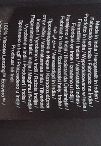 Etichetta in tessuto nero con testo stampato bianco. Include diverse lingue che riportano "Made in India" e "100% Viscose Lenzing™ Ecovero™."