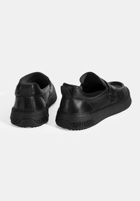 Zwarte leren sneakers met een instapontwerp, een getextureerde rubberen zool en een geometrisch patroon op de hak. Glad afwerking en gevoerde kraag.