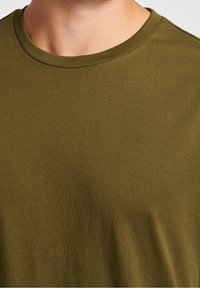 Olivengrøn t-shirt lavet af blødt, strækbart stof. Rund hals med en glat tekstur, der har et enkelt, minimalistisk design.