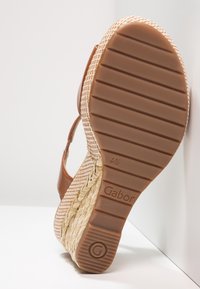 Sandale compensée en cuir marron avec plateforme en jute tressé. Semelle extérieure en caoutchouc texturé avec un motif rayé. Nom de la marque "Gabor" embossé.