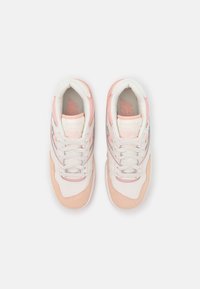 Paire de baskets blanches et roses avec lacets, vues de dessus sur un fond blanc.