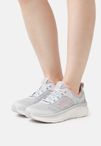 Ljusgrå sportskor med mesh-överdel, rosa detaljer och snörning. Tjock vit sula för dämpning och stöd. Märkbart logotyp på sidan.