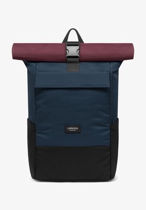Plecak rolowy z buraczkowym klapkiem, granatowym korpusem, czarnym dnem, przednią kieszenią oraz z zamknięciem na czarną plastikową klamrę.