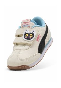 Baskets pour tout-petits Puma en crème avec des accents noirs, doublure bleue et un patch en forme de chat sur la sangle velcro. Design léger et sportif.