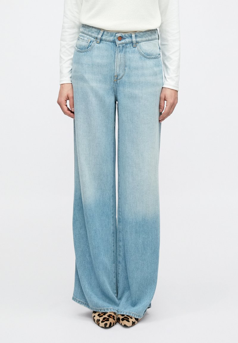 Φαρδιά τζιν παντελόνια σε ανοιχτό μπλε χρώμα με ξεθωριασμένο πλύσιμο, σχέδιο με πέντε τσέπες και εξαρτήματα σε χρυσό τόνο. Το ύφασμα έχει απαλή υφή.