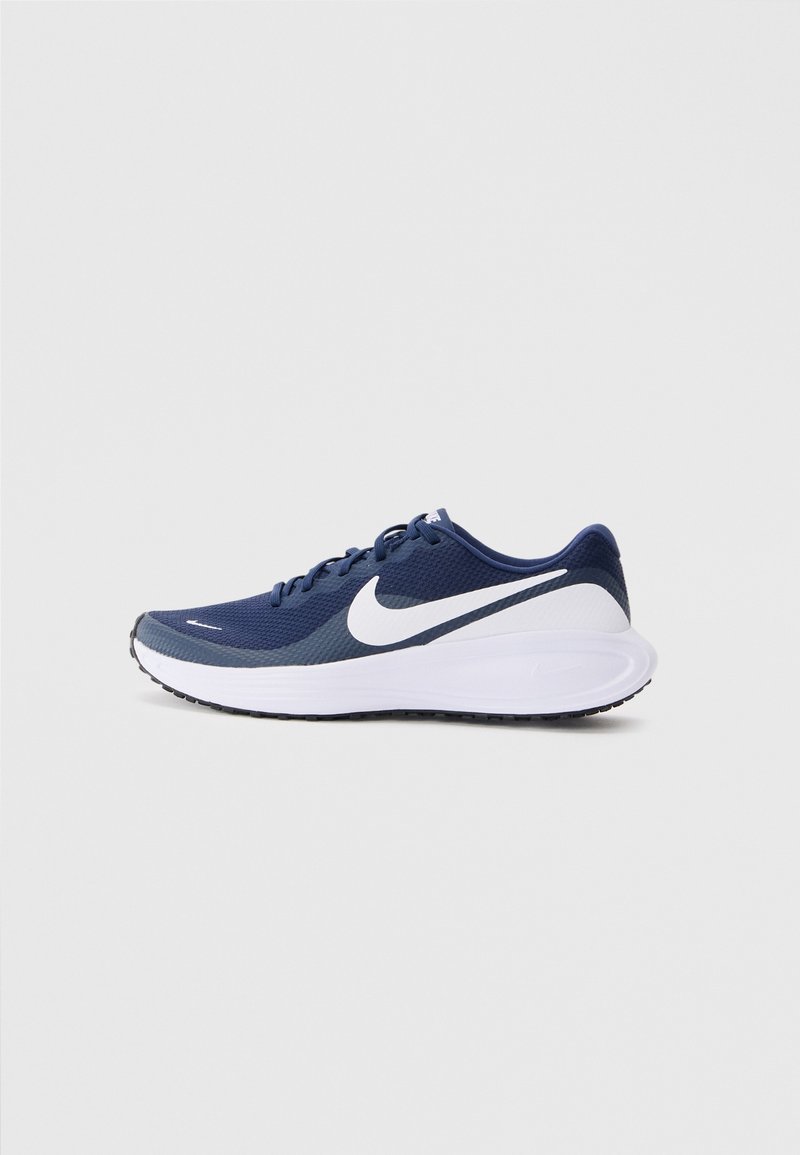 Basket athlétique bleu marine avec semelle blanche et grand logo swoosh blanc, vue de côté sur fond gris clair.