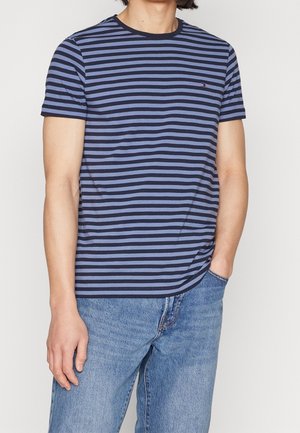 Granatowo-niebieska koszulka w paski o krótkich rękawach i okrągłym dekolcie. Na piersi znajduje się małe logo. Swobodny krój.