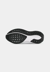 Talpa de sneaker alb-negru prezintă o suprafață din gumă texturată cu un model hexagonal, oferind tracțiune și stabilitate.