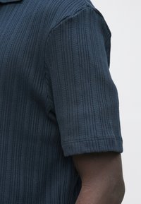 Mørkeblå ribbestrikket polo med korte ermer, med teksturert finish og avslappet passform.