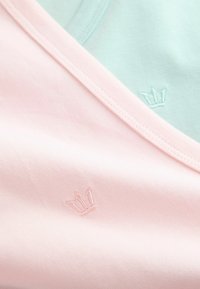 Tissu doux rose et bleu clair se chevauchant, chacun avec un petit emblème de couronne cousu près du bord.