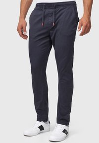 Navy blue stretch pants made of lightweight cotton, featuring an elastic waistband with drawstrings, side pockets, and a slim fit design.